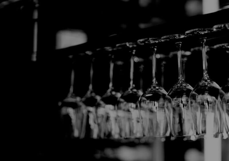 black and white image of wine glasses hanging upside down on bar rack