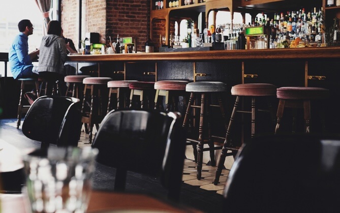 far shot of two men sitting at a bar day drinking