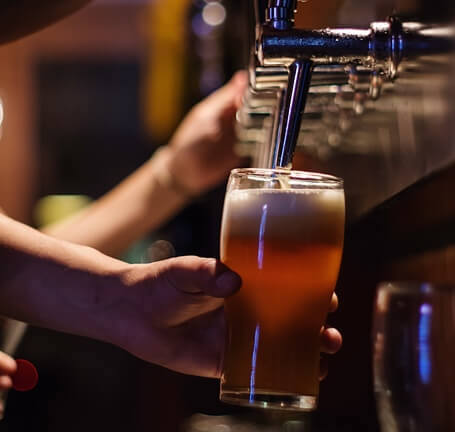 ale being poured into a pint glass from a row of taps